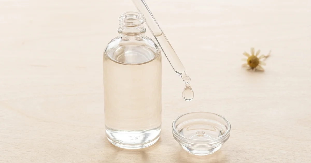 Flacon de glycérine végétale transparente avec pipette sur surface en bois clair
